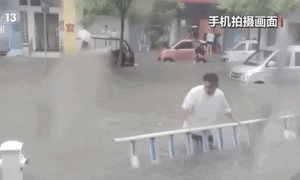 暴雨致排水井盖被冲开，担心车辆和行人发生意外，河南漯河一市民化身雨中“警示牌”缩略图